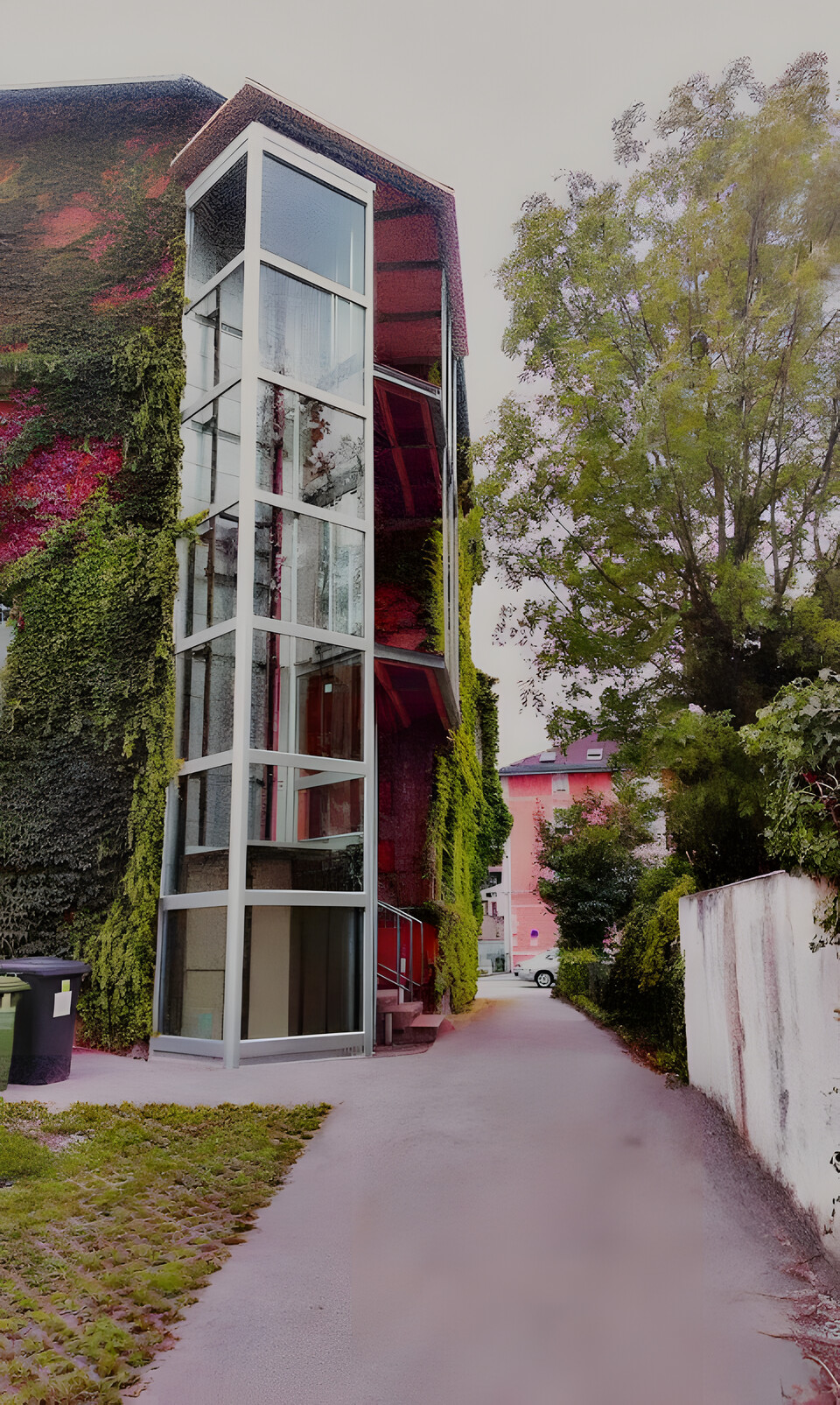 Außenliegender Glasschacht an efeubewachsener Fassade