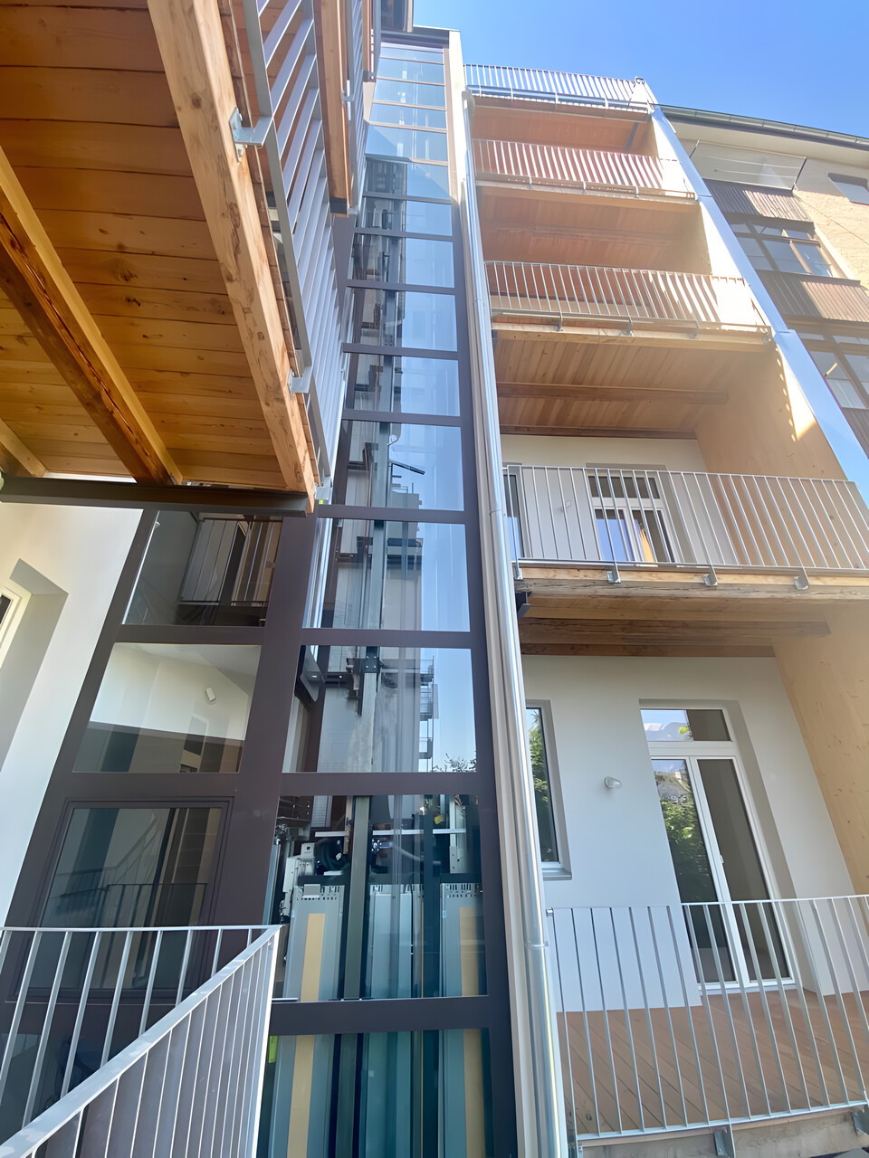 Glasschacht an Holzfassade mit Balkonen